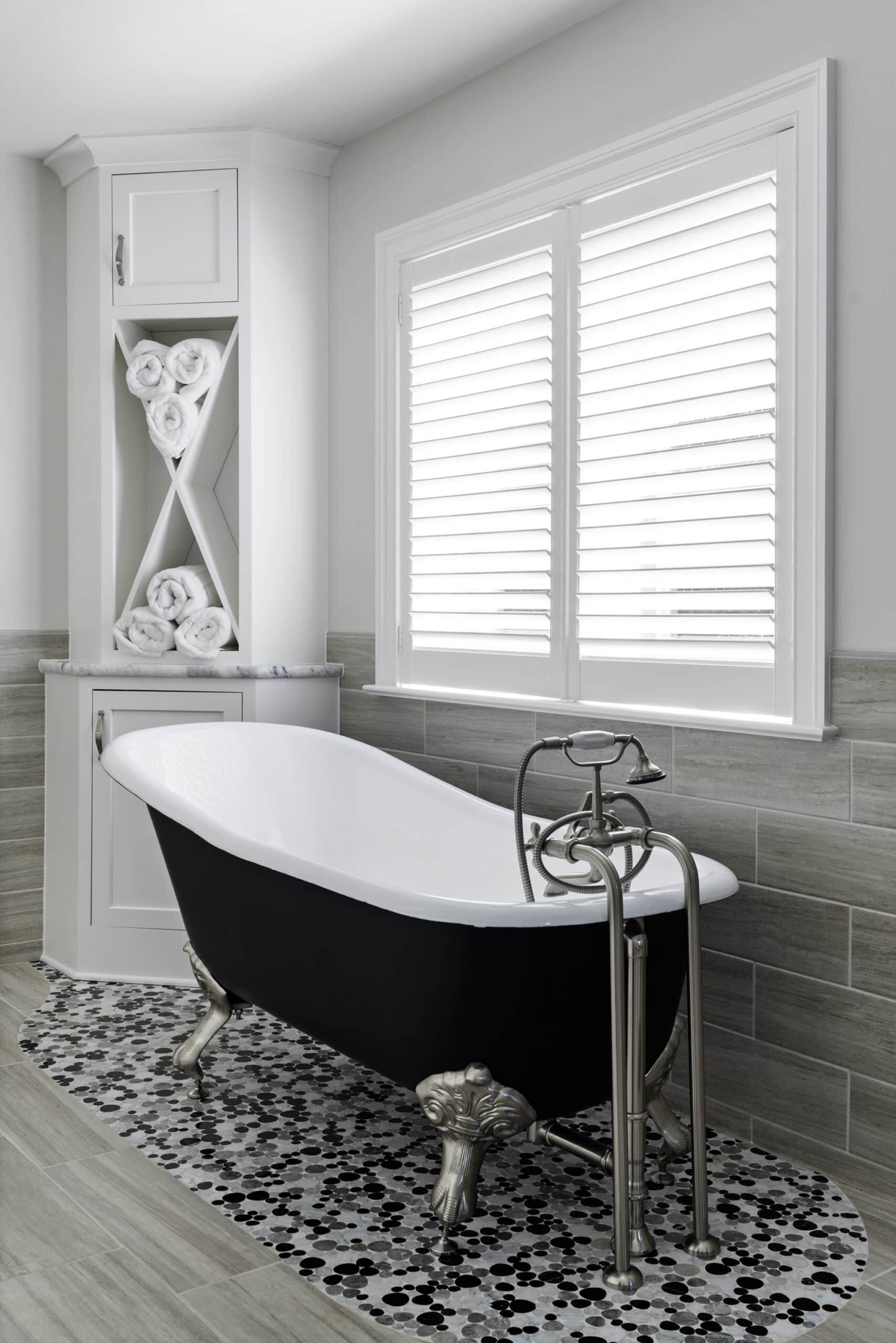 close-up of black and white clawfoot tub in front of a large white window  