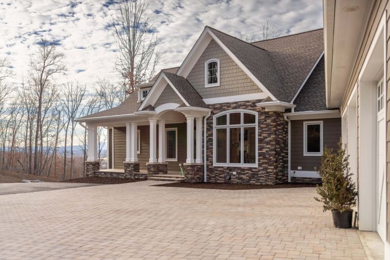 house exterior, brick facia with white columns, door, and window trim. expansive light colored stone groundwork in front of house.