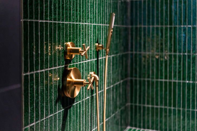 emerald green shower walls with vintage style brass knobs and a vertical brass water spout