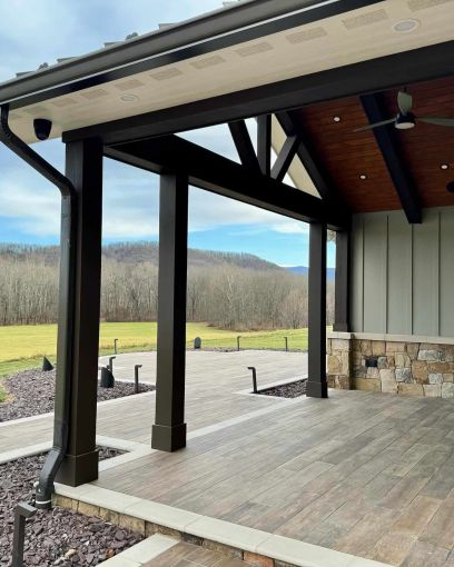 a rustic porch with wooden walkways framed with stone, woodlands are in the background