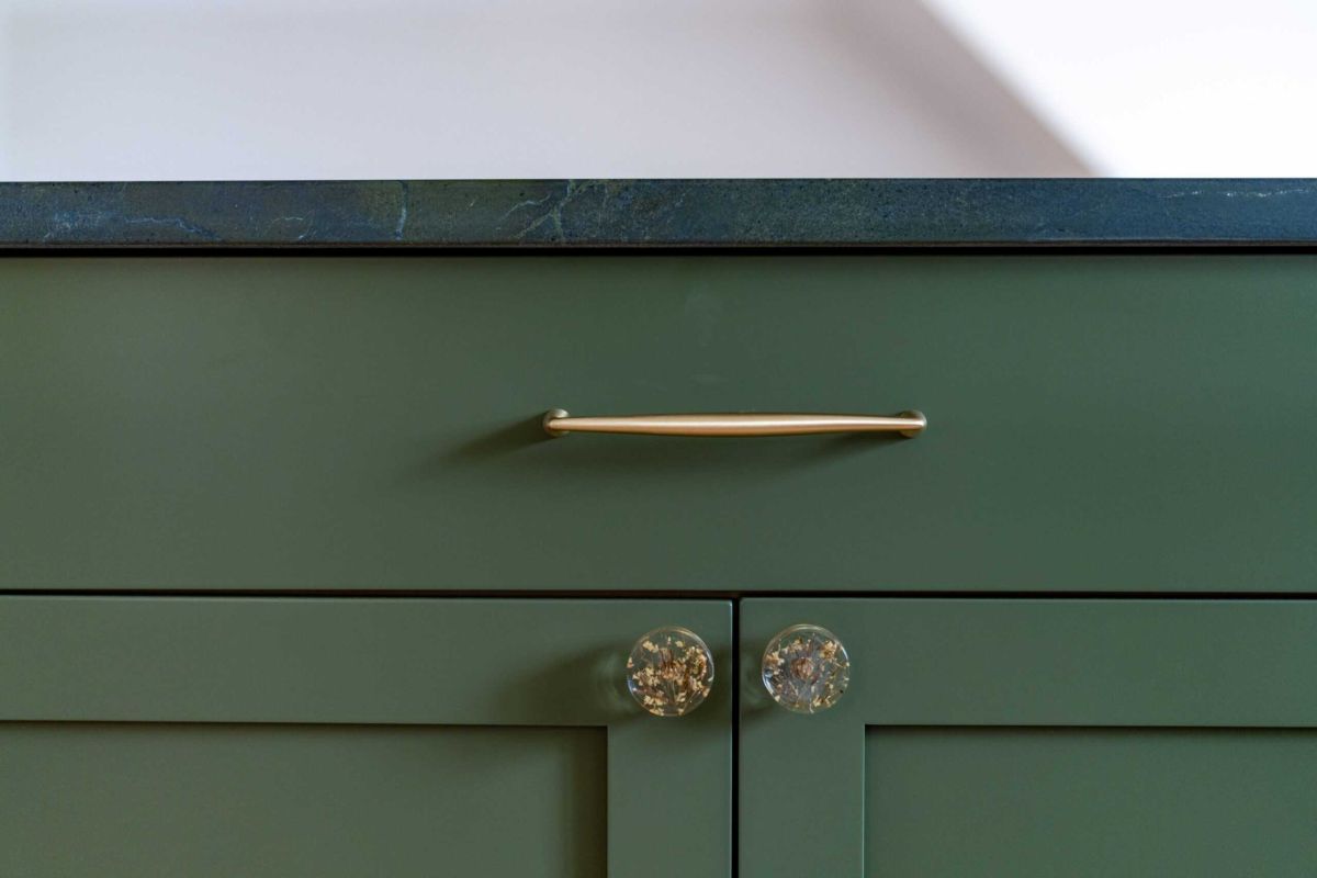 tightly cropped photo of a green cabinet with decorative handles which are transparent and have flowers within