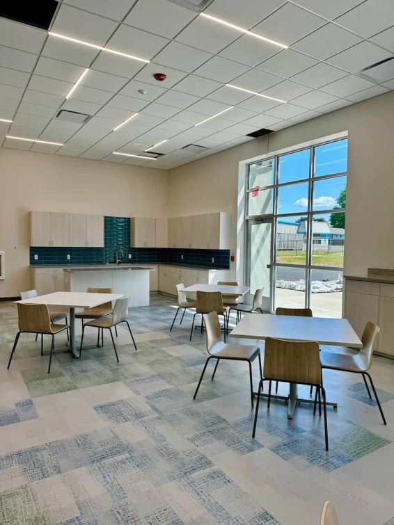 office break room with faded color floor tiles and  thin bar ceiling lights. 