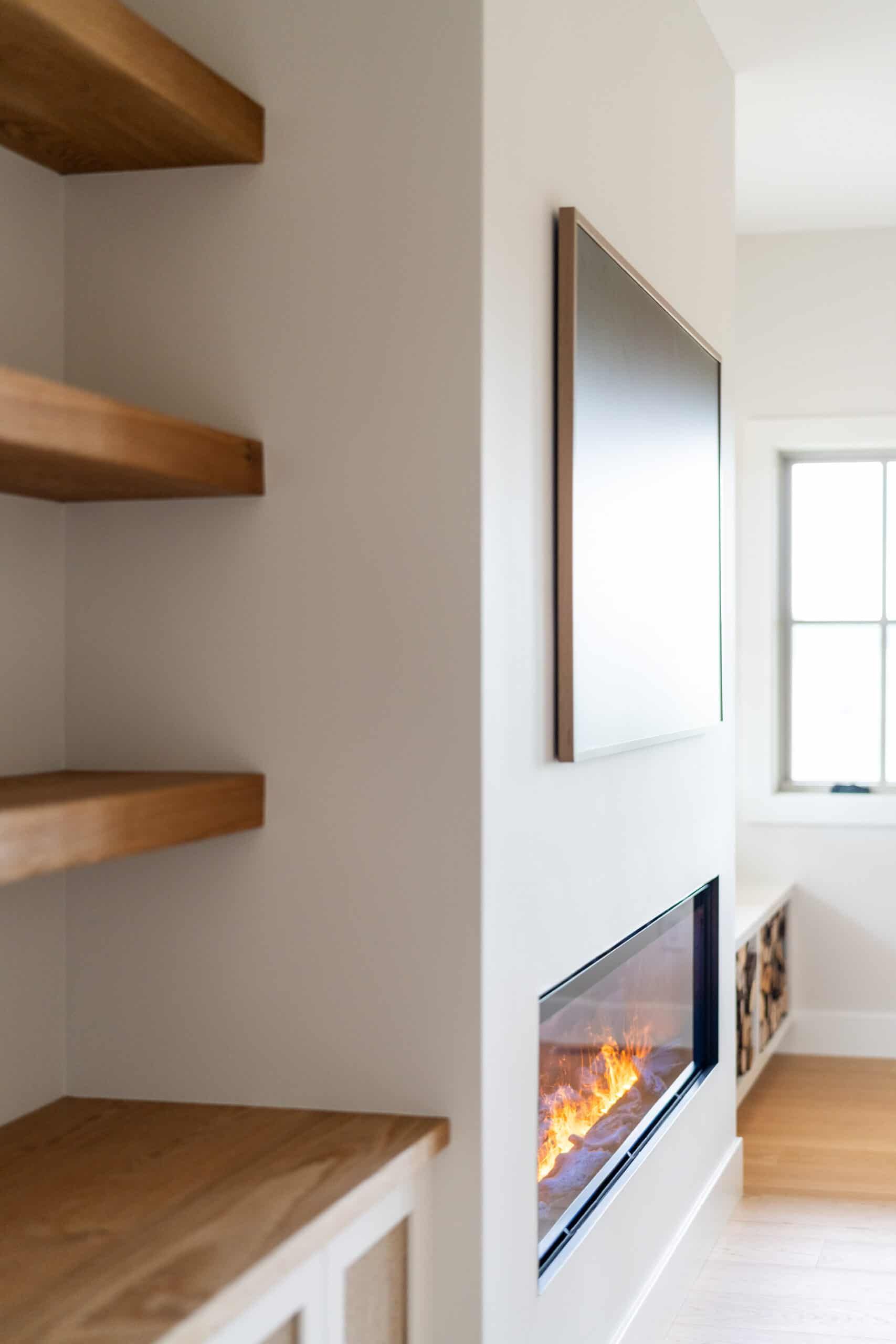 Close-up of brightly lit family room wood shelves, flat screen TV, and fireplace as seen from three-quarter perspective