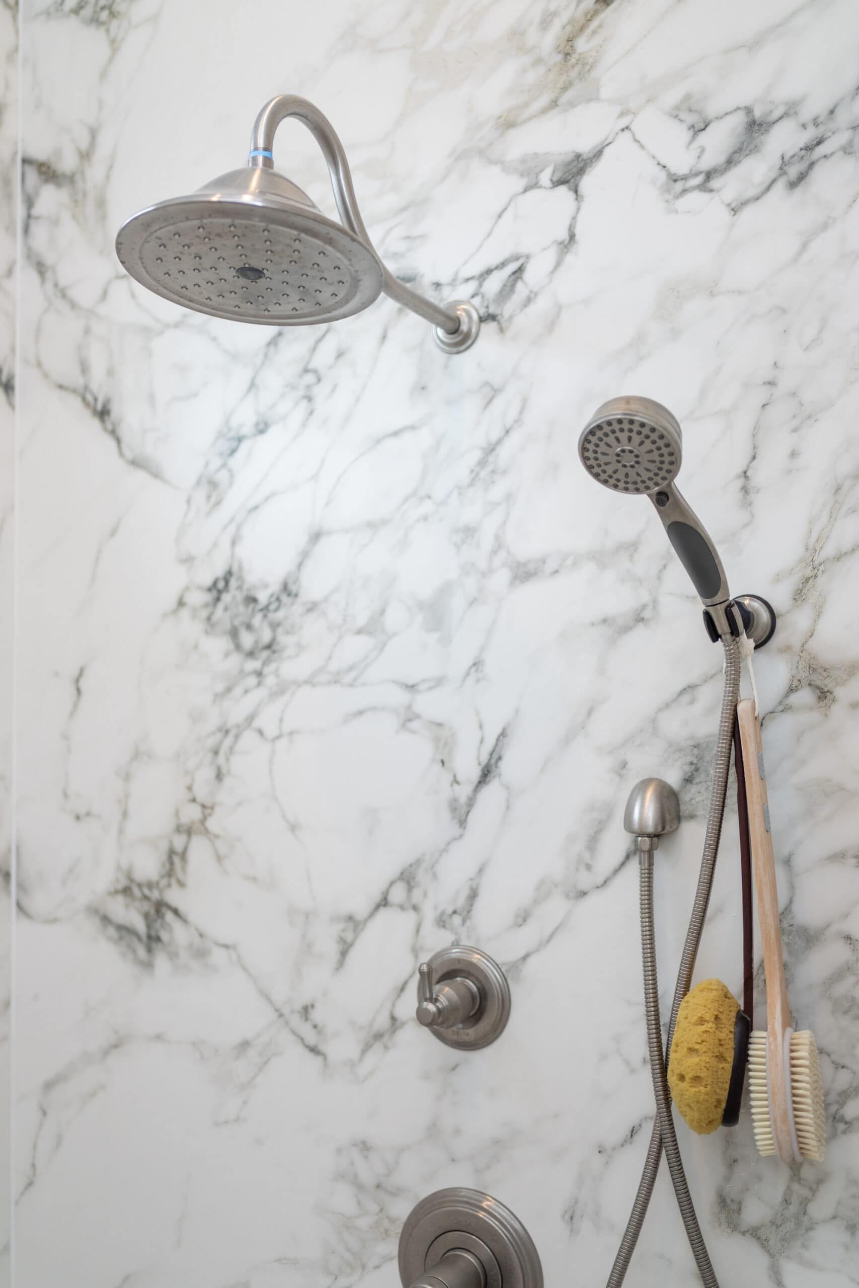 close-up shot of white granite shower wall with metal water features